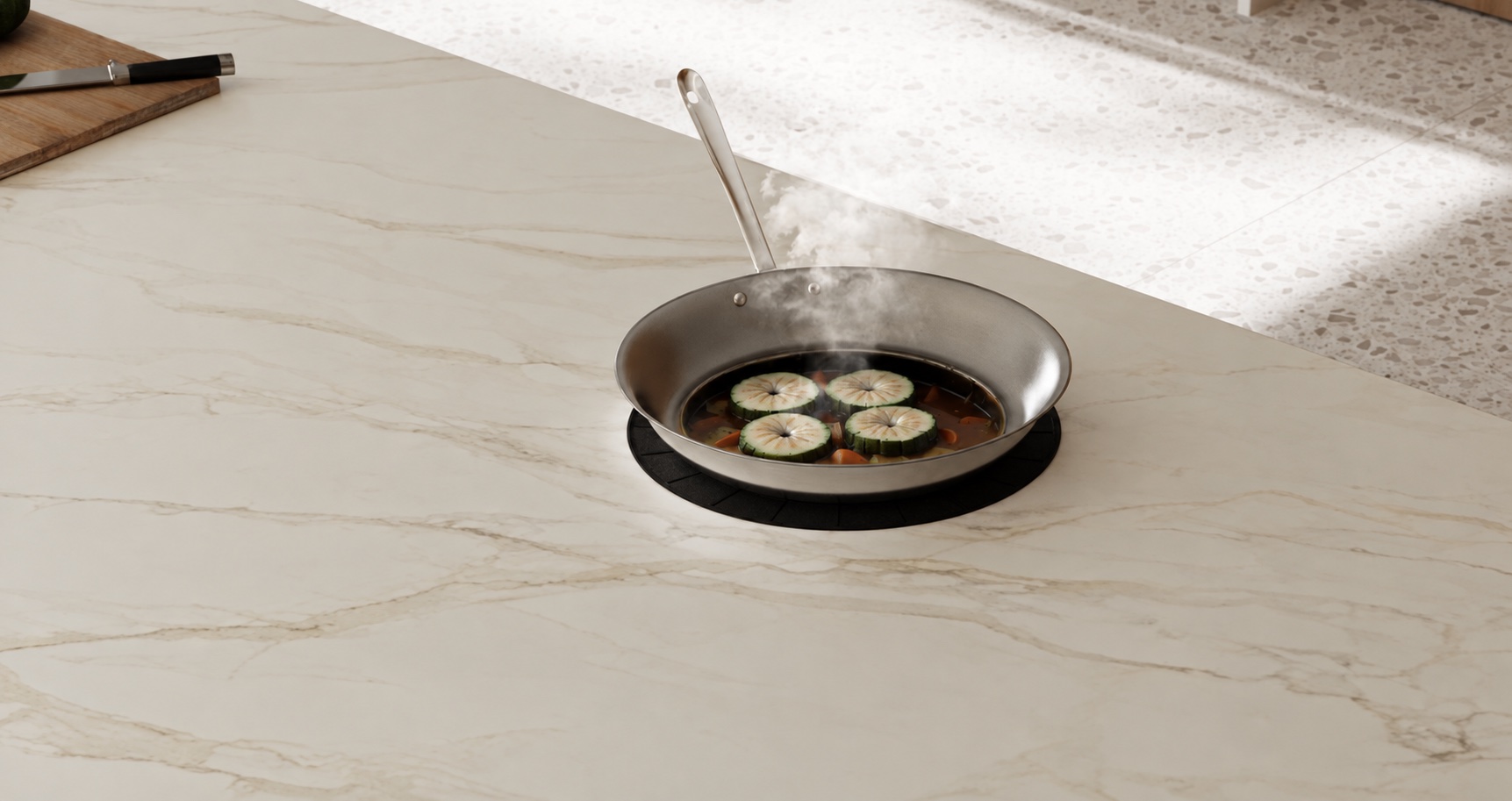 A steaming stainless steel pan on a black cooking mat over a seamless pale countertop